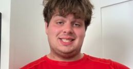 Smiling young man wearing a red Puma shirt, showcasing a casual style with a friendly demeanor.