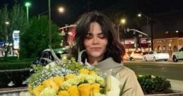 Maddie Jackson smiles while holding a large bouquet of yellow flowers on a city street at night.