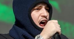 Yeat performing live, showcasing his unique style with tattoos and a distinctive hood, captivating the audience with energy.