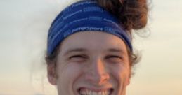Young man with a playful hairstyle, smiling against a scenic outdoor sunset background, showcasing a vibrant personality.