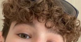 Cheerful young boy with curly hair and sunglasses giving a peace sign, showcasing a playful personality. Perfect for Daniell!