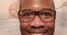 Smiling man in glasses wearing a gray shirt, with a decorative background, exuding a friendly and welcoming vibe.