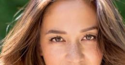 Shannon Chan Kent with flowing, wavy hair, natural makeup, and a serene expression amidst a vibrant outdoor background.
