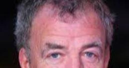Jeremy Clarkson with a serious expression, wearing a dark suit and patterned tie, at a formal event.