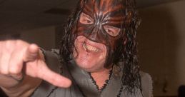 Abyss wrestler in mask poses fiercely, showcasing his intense persona and unique attire at an event filled with fans.