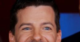 Sean Hayes smiling widely at a red carpet event, showcasing his charming personality and stylish black attire.