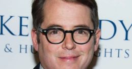 Matthew Broderick smiles at a red carpet event, showcasing his signature glasses and stylish attire, exuding charm and elegance.