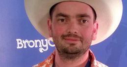 Man in a cowboy hat and floral shirt at BronyCon, smiling against a blue backdrop with BronyCon branding.