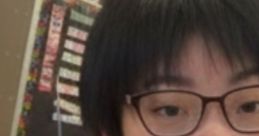 Young person with glasses smiling slightly, showcasing natural lips against a classroom background.