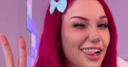 Vibrant, playful portrait of a woman with pink hair and a blue bow, flashing peace sign and playful expression.