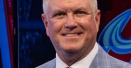 Marc Moser, Colorado Avalanche broadcaster, smiling in a stylish light blue suit and pink tie, ready for a game.