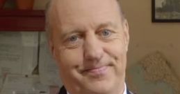 Smiling man in formal attire with pins, representing Mr. Perkins' character in a comedic or dramatic setting.
