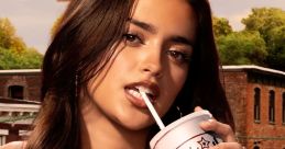 Noa Olivar from Pretty Little Liars: Original Sin enjoys a drink, showcasing a stylish beach vibe in vibrant attire.