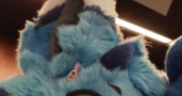 Blue fursuit character with cute features, smiling and waving, embodying playful spirit of furry conventions and fandom.