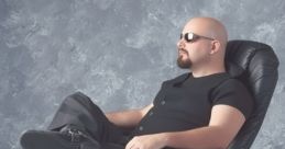 Brian F. Sousa relaxes in a stylish chair, showcasing a confident and laid-back demeanor, wearing sunglasses and casual attire.
