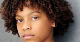 Young boy with curly hair, showcasing confidence and style, dressed in a black sweater against a neutral background.