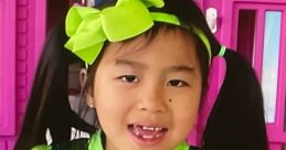 Girl in a sparkling green dress with a bow, standing in front of a colorful playhouse, embodying the joy of Jannie Toys And Colors.