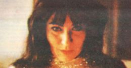 Louise Huebner, a witch, gazes intently into the camera, illuminated by candlelight in a mystical setting.