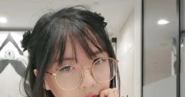 Lilypichu in a stylish black outfit, wearing glasses, with a thoughtful expression in a modern indoor setting.