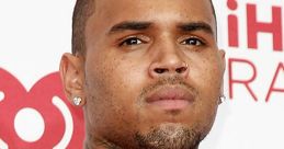 Chris Brown showcasing his unique style at an event, featuring tattoos and a bold fashion statement with a gold chain.