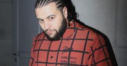 Navai poses confidently in a bold red checkered outfit, showcasing his unique style and personality in a modern setting.