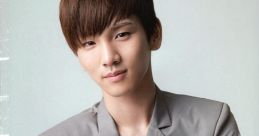 Key from SHINee poses confidently in a stylish gray blazer, showcasing his signature charm and fashion sense.