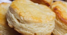 Fluffy, golden-brown biscuits stacked in a basket, perfect for breakfast or a comforting snack. Savory goodness awaits!