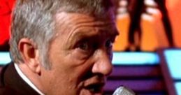 Damon Killian announces a challenge in "The Running Man," gripping a microphone with intensity on stage.