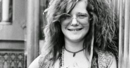 Janis Joplin poses confidently, showcasing her iconic bohemian style with layered jewelry and a playful expression.