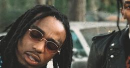 Quavo from Migos performing with passion, showcasing his signature style and jewelry in an urban setting.