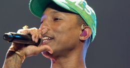 Pharrell Williams performs passionately in a colorful tie-dye shirt and vibrant cap, captivating the audience with his energy.