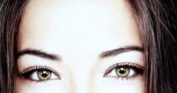 A close-up portrait of a woman with striking green eyes and long dark hair, showcasing natural beauty and elegance.