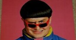 Oliver Tree poses with a playful expression, wearing stylish shades and a colorful jacket, embodying pop culture vibes.
