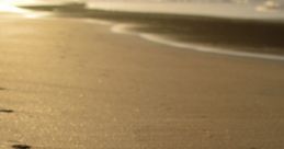 Serene footprints on glistening sand at sunset, symbolizing tranquility and the beauty of nature's shoreline.