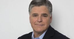 Sean Hannity poses confidently with arms crossed, wearing a blazer and light blue shirt, showcasing a professional demeanor.