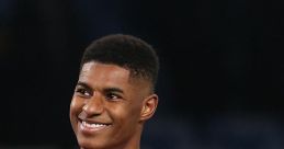 Marcus smiles and celebrates on the football pitch, wearing a red Manchester United jersey during a match.