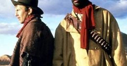Two cowboys stand in a desert landscape, showcasing classic Western attire and a dramatic sky, reminiscent of cowboy culture.