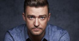 Justin Timberlake poses thoughtfully with hands clasped, wearing a blue shirt against a dark background, showcasing his charisma.