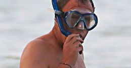 Jeremy Clarkson snorkeling in the sea, wearing a mask and snorkel, amidst a relaxed beach atmosphere.