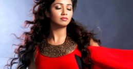 Shreya Ghoshal in a stunning red outfit, showcasing her elegance and grace in a dramatic pose against a dark background.