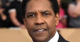 Denzel Washington poses confidently at a red carpet event, showcasing his iconic style and charisma in a classic black suit.