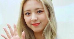 Yuna from ITZY smiling and waving while wearing a crown, showcasing her charming personality and stage presence.