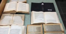 Scattered open books on a table in a library, showcasing worn pages and diverse texts. Perfect for a rainstorm reading session.