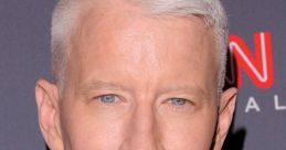 Anderson Cooper at a media event, showcasing his signature silver hair and sharp suit in front of a CNN backdrop.