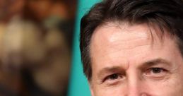 Giuseppe Conte smiles confidently against a backdrop of Italian flags, representing his leadership and political presence.