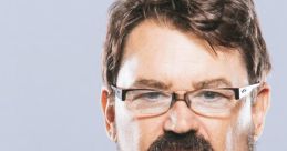 Tony Schiavone, renowned wrestling commentator, showcases a serious expression in a stylish suit and tie.
