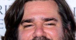 Matt Berry smiles confidently, showcasing his distinctive beard and long hair at a formal event, exuding charisma.