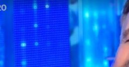 Christian De Sica smiles on stage, showcasing his comedic talent against a vibrant blue backdrop, captivating the audience.