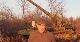 Evgeny Prigozhin stands before a military tank in an outdoor setting, showcasing a moment of military presence.
