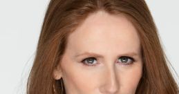 Catherine Tate with long, wavy red hair, wearing a navy blouse, showcases a confident expression and striking blue eyes.